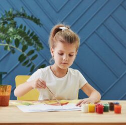Gentle moves. Little girl is drawing by using gouache and brush. Learning in the art class