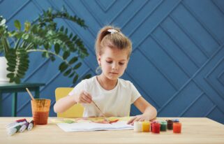 Gentle moves. Little girl is drawing by using gouache and brush. Learning in the art class