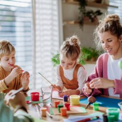 Happy family with little kids decorating easter eggs.