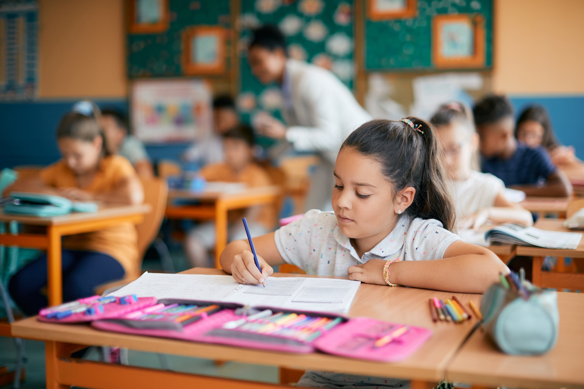 Little girl writing in notebook while having a class at elementary school.