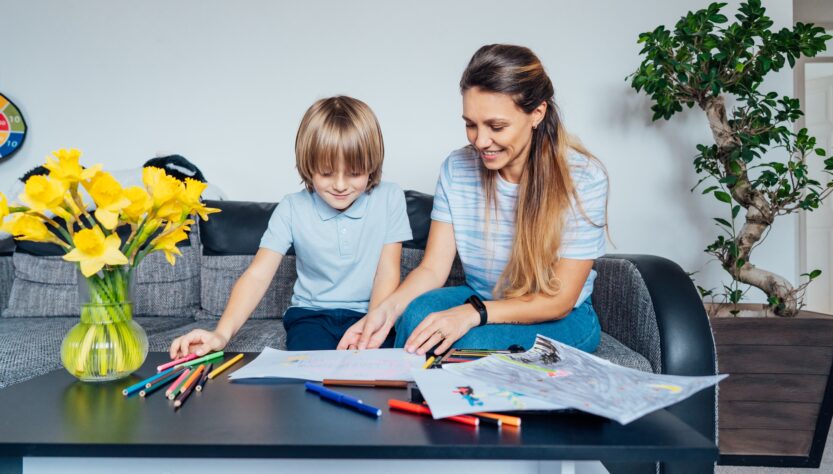 Mother and son drawing with color pencils and markers in the living room. Child creativity concept.