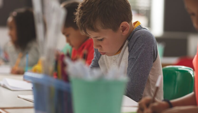 School boy writing a dictation on a notebook in a classroom