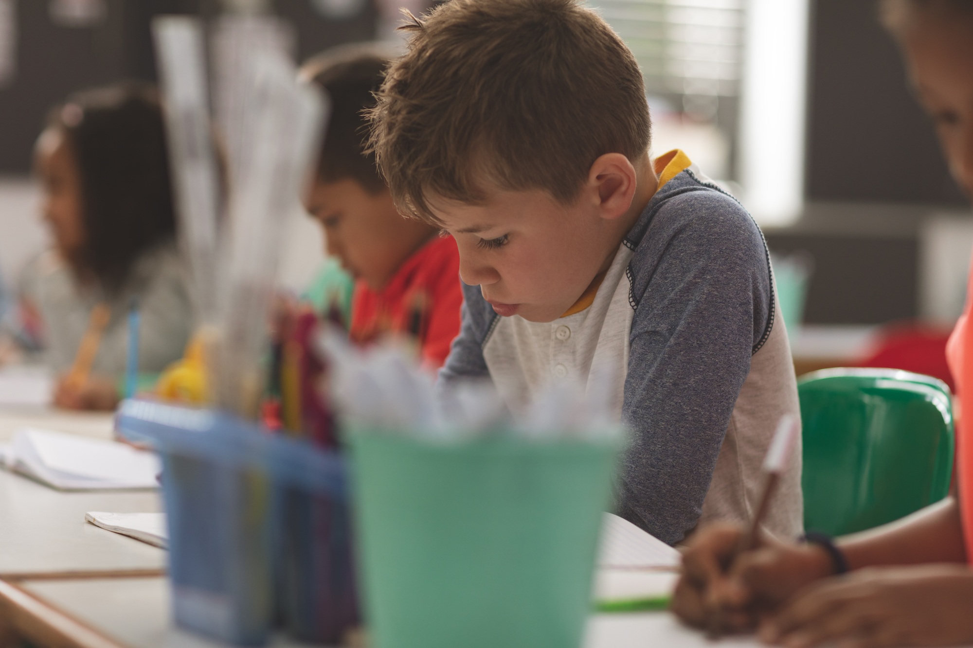 School boy writing a dictation on a notebook in a classroom